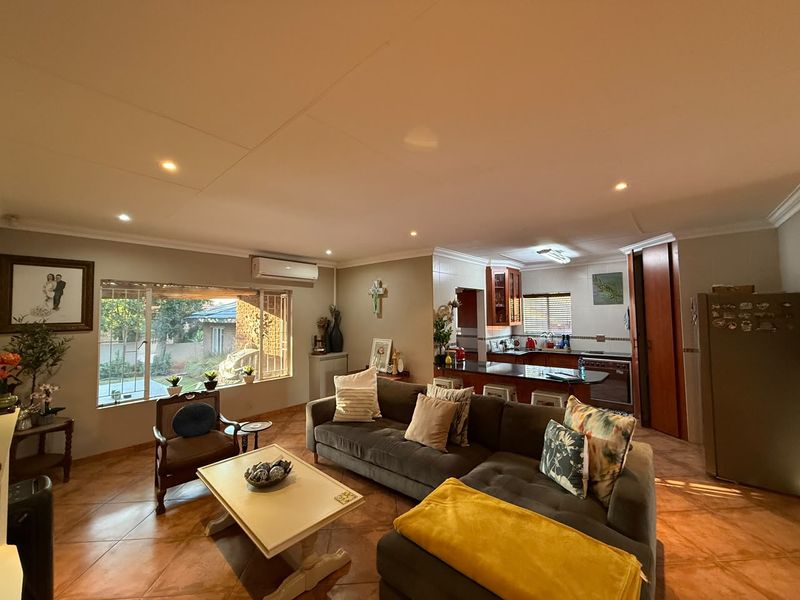 Open-plan living area featuring tiled floors, recessed lighting, and a functional kitchen with built-in cabinetry and appliances, creating a connected and versatile living space.