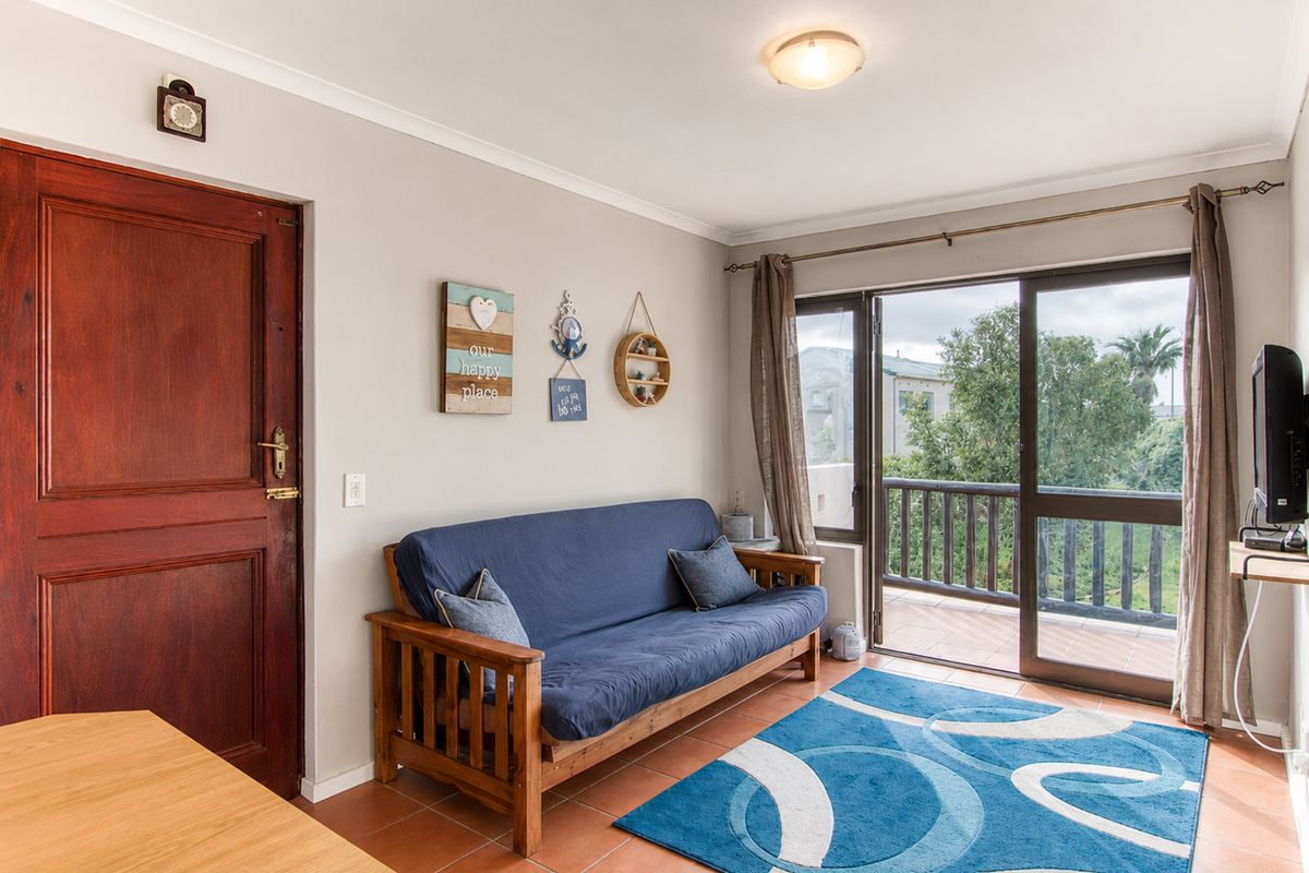 A living room featuring tiled flooring and a sliding glass door providing direct access to an outdoor balcony area.