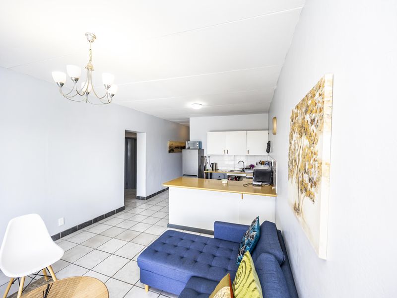 Open-plan living area featuring a functional kitchen with laminate countertops and tiled flooring throughout, creating a cohesive and practical living space.