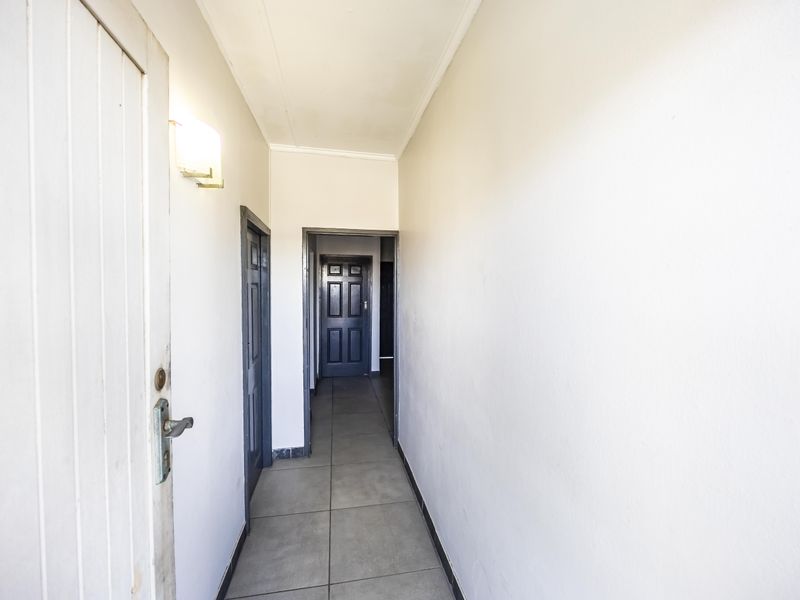 A functional hallway featuring tiled flooring and neutral walls, providing access to multiple internal rooms within the apartment.