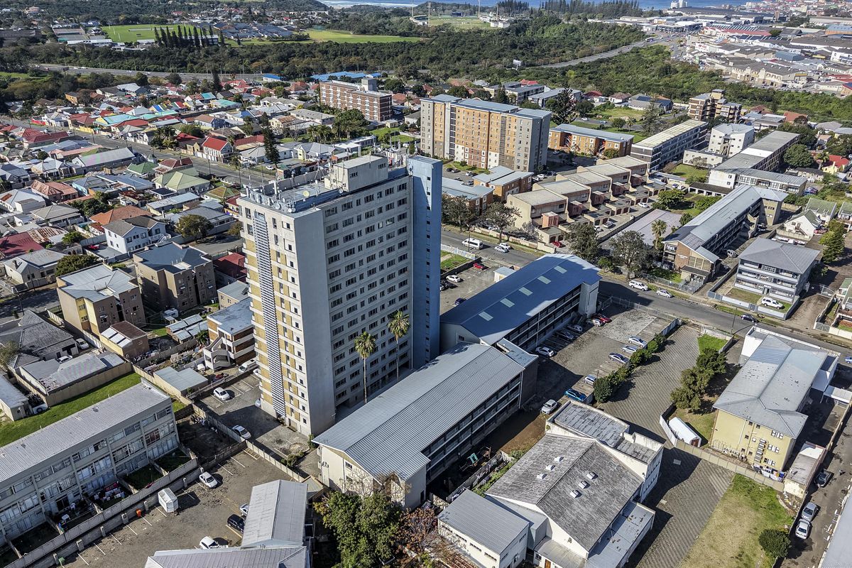 Aerial view of a high-rise apartment complex situated within a dense urban residential neighborhood.