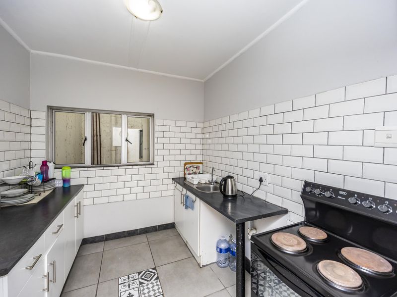 Functional kitchen featuring white subway tile backsplash, dark laminate countertops, tiled flooring, and a freestanding electric stove.
