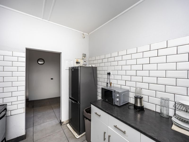 A functional kitchen featuring a subway tile backsplash, dark laminate countertops, base cabinetry, and tiled flooring, providing a practical workspace.
