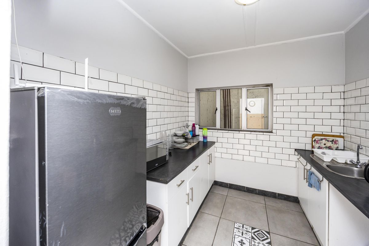 A functional kitchen featuring white cabinetry, dark laminate countertops, a subway tile backsplash, and a stainless steel sink with a mixer tap.