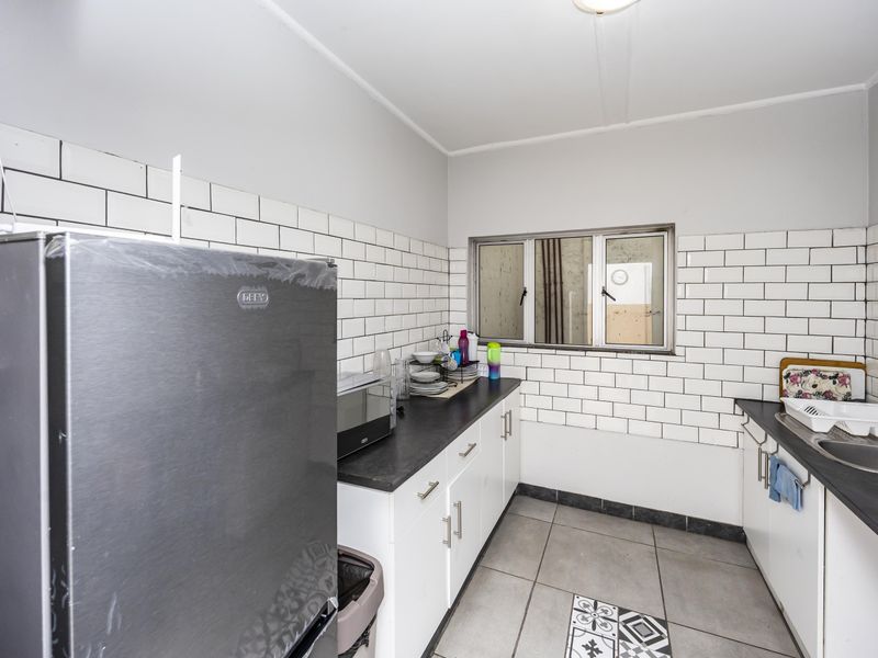 A functional kitchen featuring white cabinetry, dark laminate countertops, a subway tile backsplash, and a stainless steel sink with a mixer tap.