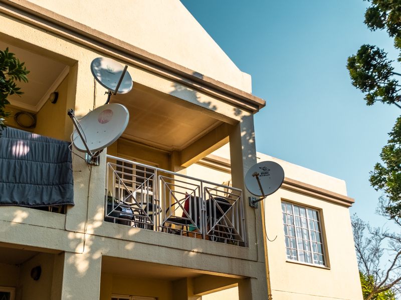 A view of an apartment balcony featuring a metal balustrade and multiple satellite dishes mounted to the exterior wall.