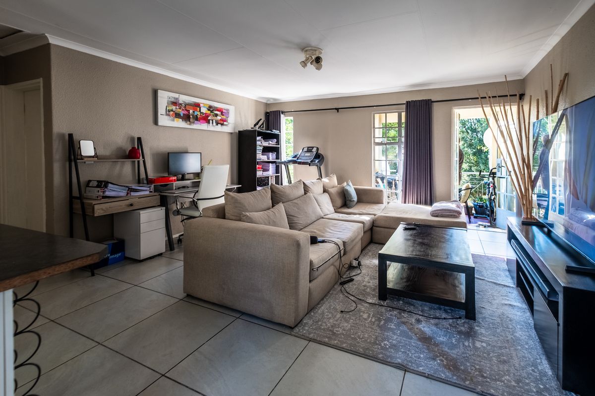 Spacious living room featuring large format floor tiles, neutral wall tones, and direct access to an outdoor balcony area.