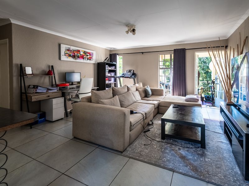 Spacious living room featuring large format floor tiles, neutral wall tones, and direct access to an outdoor balcony area.