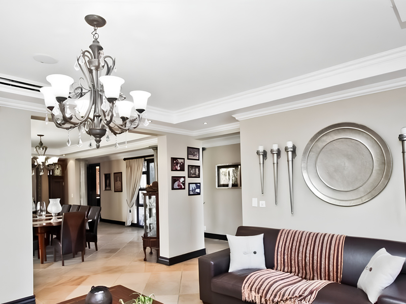 Spacious open-plan living and dining area featuring elegant crown molding, recessed lighting, and high-quality stone tile flooring throughout.