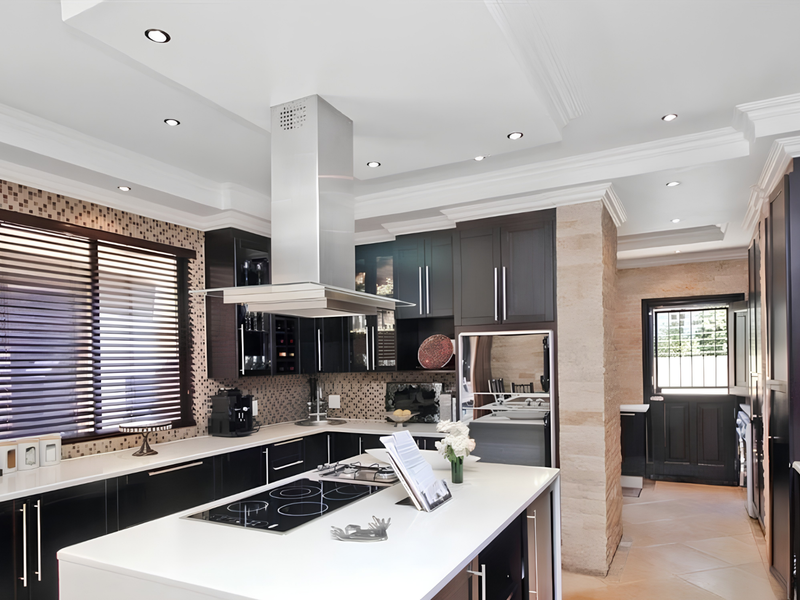Modern kitchen featuring a central island, sleek dark cabinetry, stone feature wall, mosaic backsplash, and high-end built-in appliances with recessed ceiling lighting.