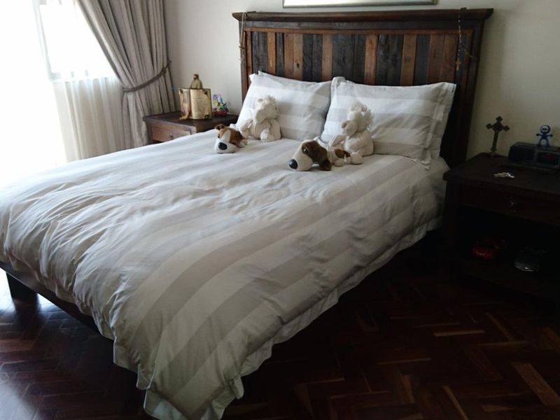 A bedroom featuring classic parquet timber flooring and neutral window treatments.