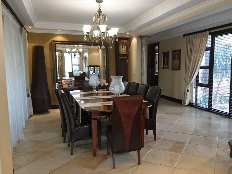 Spacious dining room featuring tiled flooring, crown molding, and a decorative column, providing an elegant setting for formal meals.
