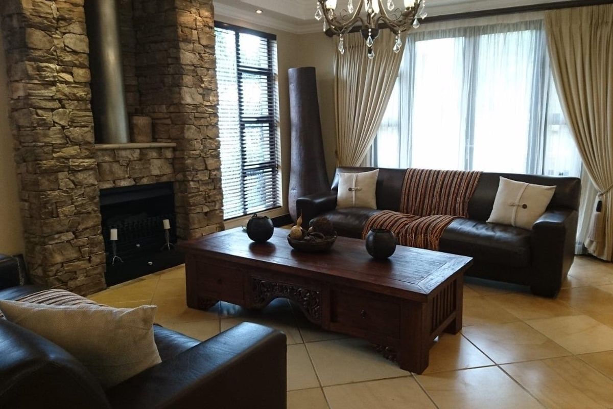 Spacious living room featuring a prominent stone-clad fireplace, large windows with natural light, and neutral tiled flooring.