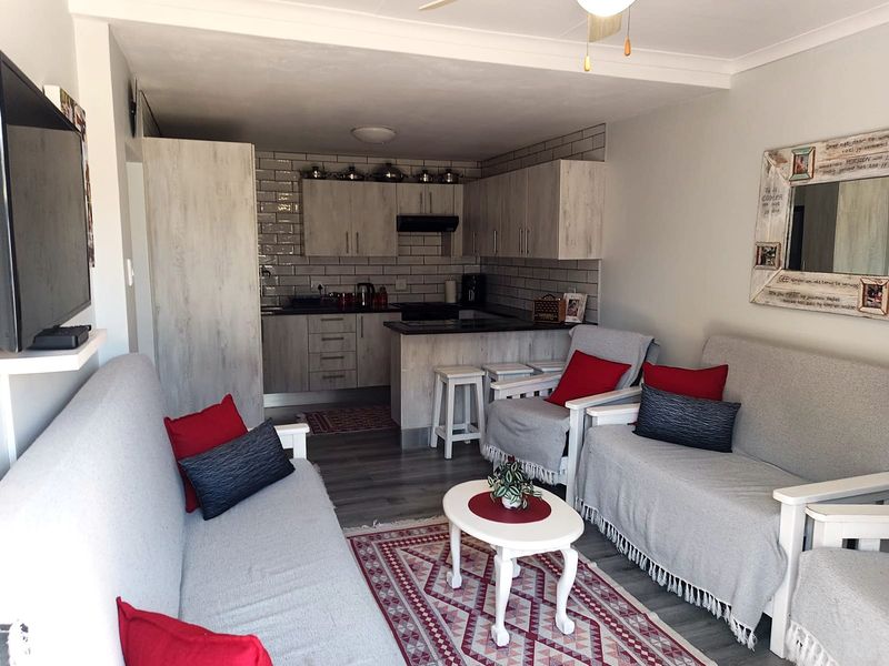 An open-plan living area featuring a modern kitchen with subway tile backsplash, built-in cabinetry, and a breakfast counter, seamlessly connected to the lounge space.