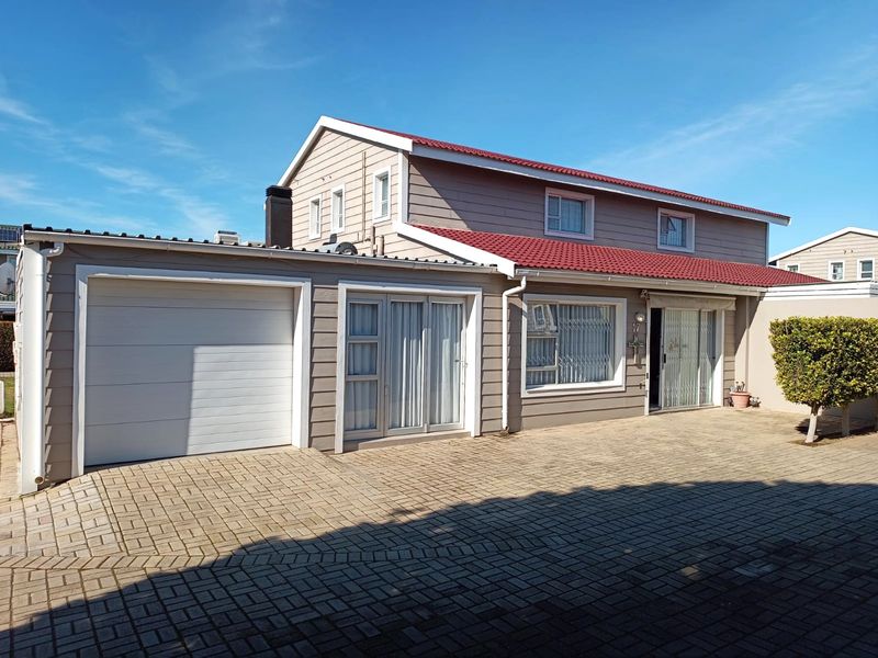 Front elevation of a townhouse featuring a paved driveway, single garage, and tiled roof with neutral siding.