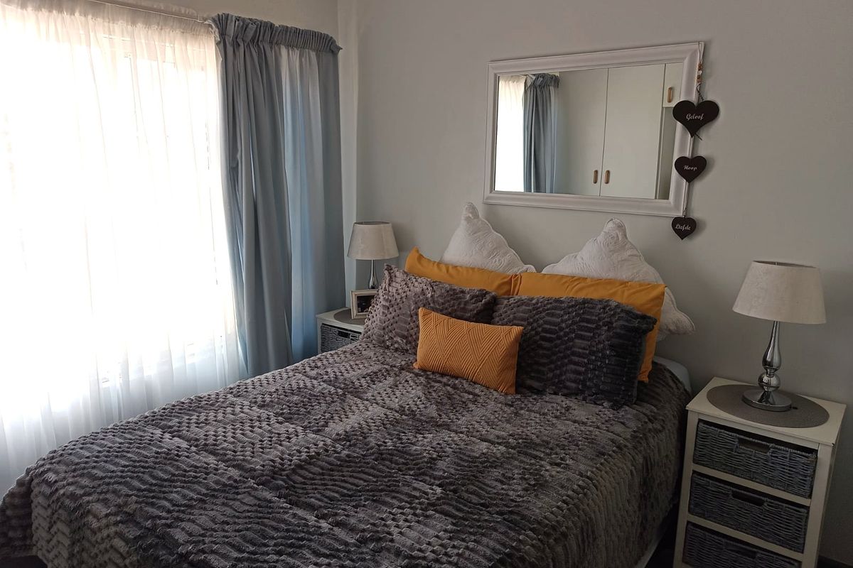 A cozy bedroom featuring built-in cupboards and natural light through large windows, providing a comfortable and functional sleeping space.