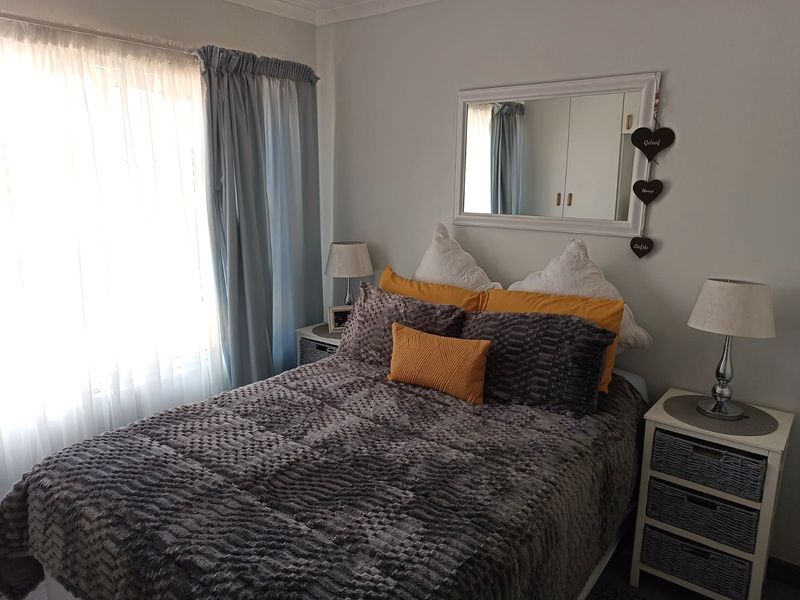 A cozy bedroom featuring built-in cupboards and natural light through large windows, providing a comfortable and functional sleeping space.