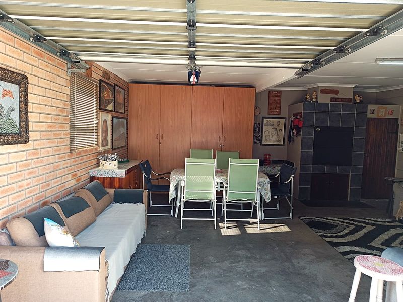 A spacious garage featuring exposed brick walls, built-in storage cupboards, and a tiled fireplace, currently utilized as a multi-purpose living and entertainment area.