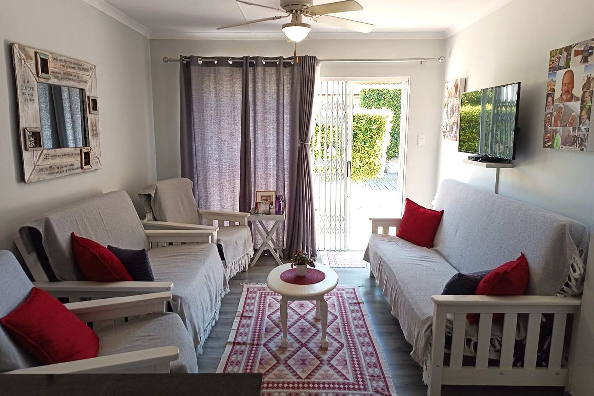 A well-maintained living room featuring laminate flooring, a ceiling fan, and a sliding glass door providing direct access to the outdoor area.