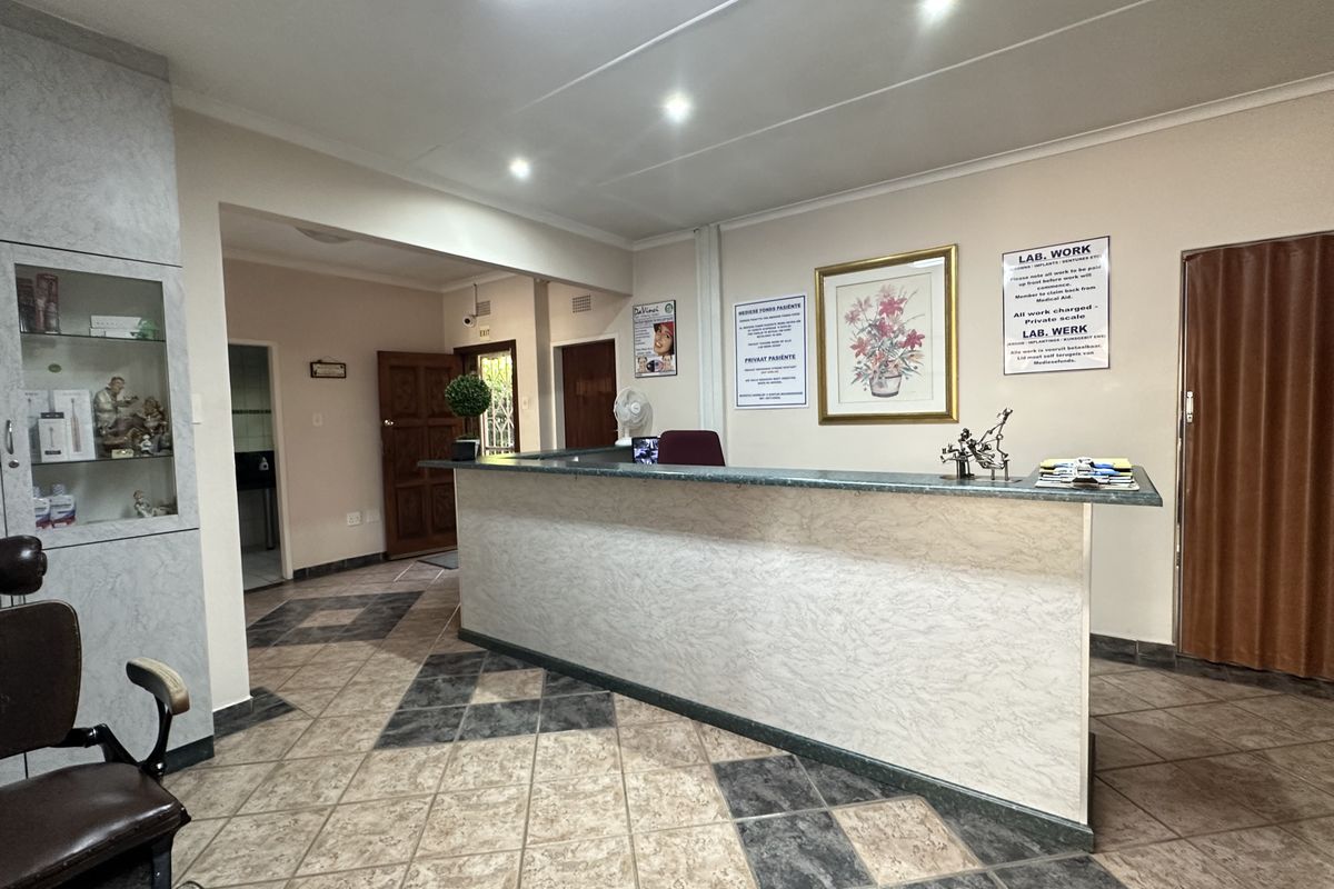 A functional reception area featuring a built-in desk, tiled flooring, and recessed lighting, suitable for a professional office or medical practice setting.