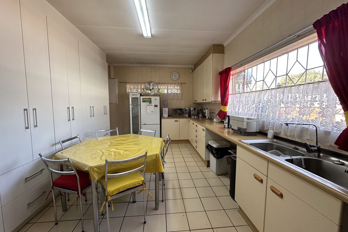 A functional kitchen featuring extensive built-in cabinetry, a double basin sink, and tiled flooring, offering a practical layout with ample storage space.