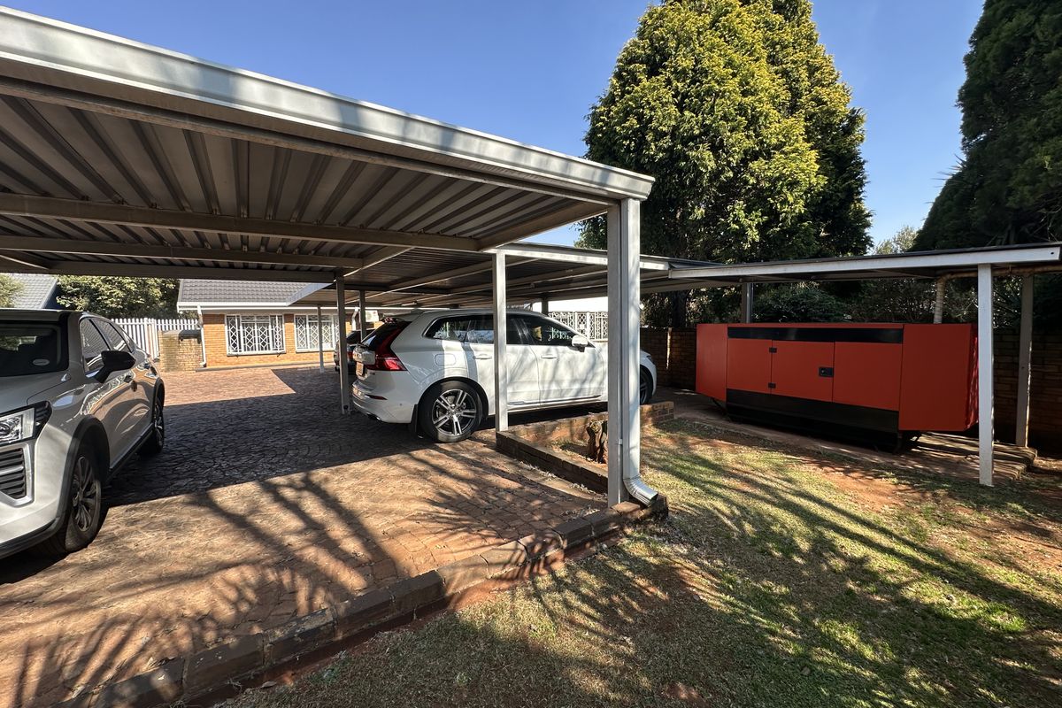 A spacious outdoor carport area with paved driveway and metal roofing, providing covered parking space for multiple vehicles.