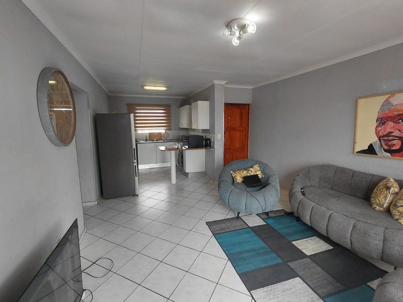 Open-plan living area featuring tiled flooring and a functional kitchen with built-in cabinetry, oven, and extractor fan.
