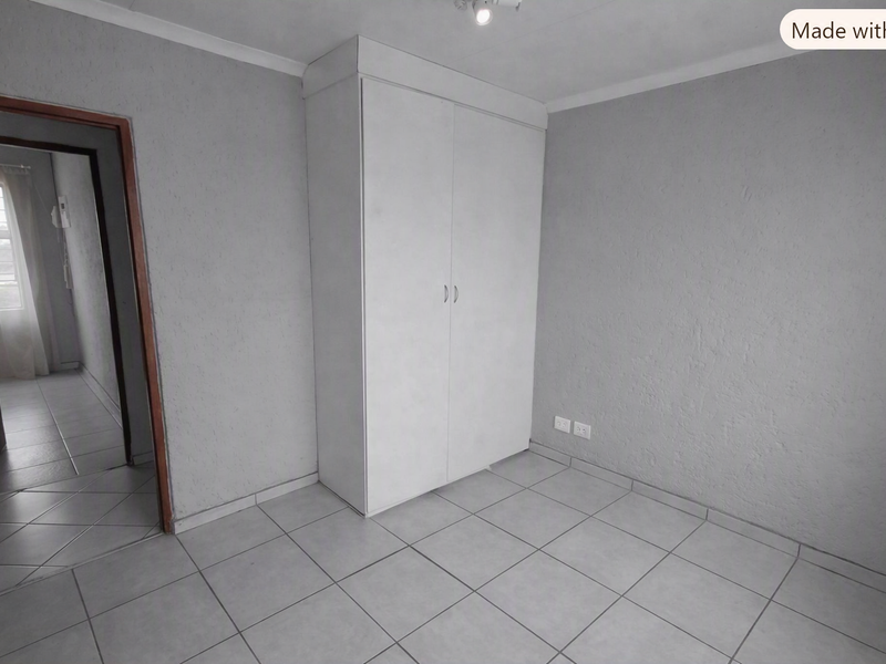 A clean, empty bedroom featuring neutral tiled flooring and a built-in wardrobe, offering a blank canvas for personalization.