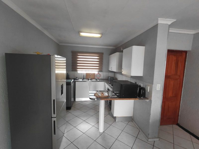 Functional kitchen featuring built-in cabinetry, a breakfast counter, tiled flooring, and a stainless steel sink with a window view.