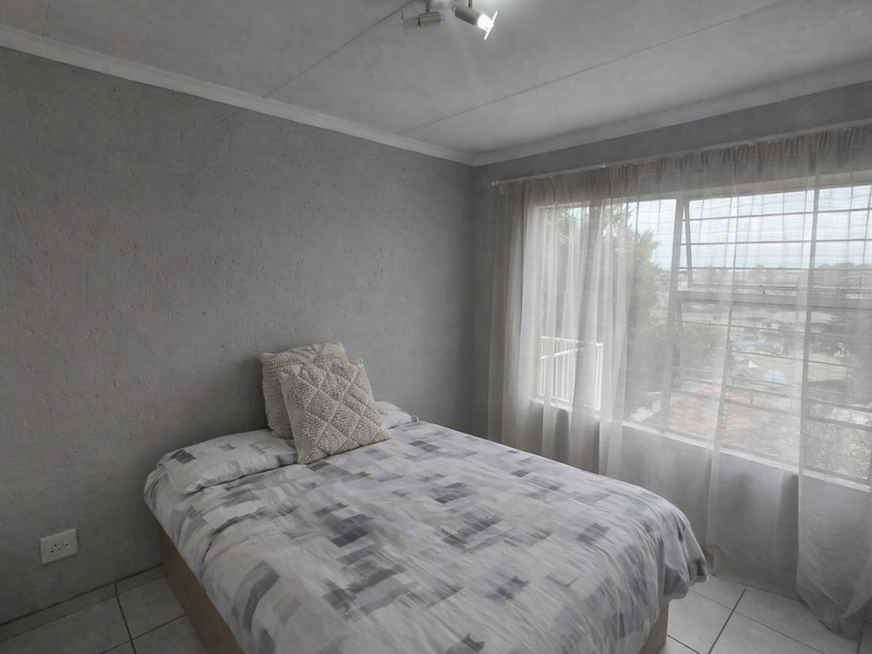 A bedroom featuring tiled flooring, security bars on the window, and a ceiling-mounted spotlight fixture.