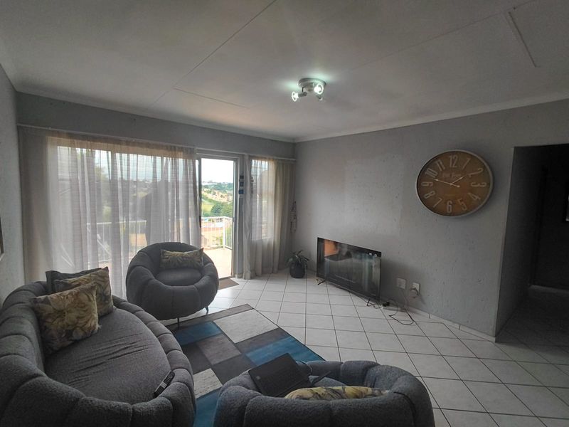 Living room featuring tiled flooring and a sliding glass door providing access to an outdoor balcony area.