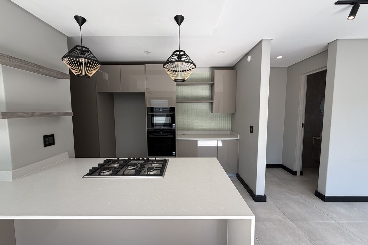 Modern kitchen featuring sleek cabinetry, stone countertops, a built-in gas hob, and an integrated oven, finished with contemporary tile backsplash and recessed lighting.