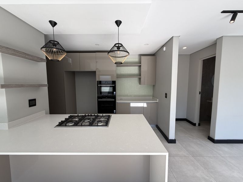 Modern kitchen featuring sleek cabinetry, stone countertops, a built-in gas hob, and an integrated oven, finished with contemporary tile backsplash and recessed lighting.