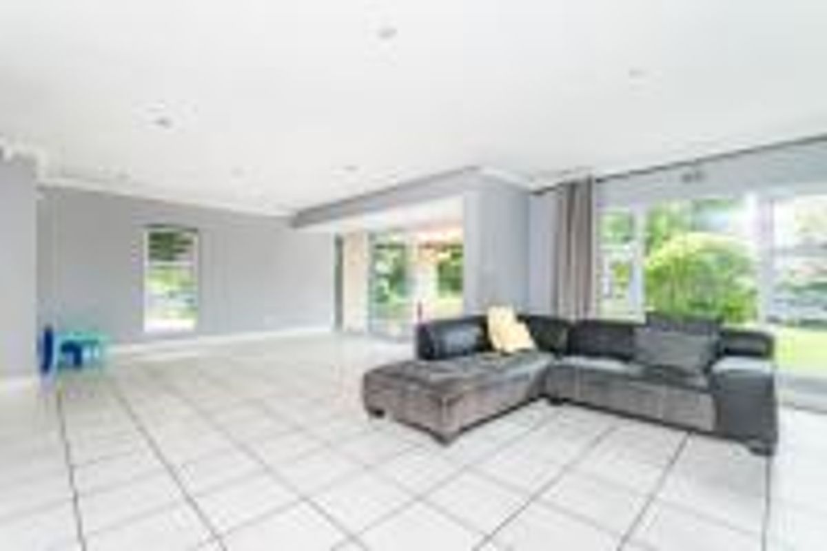 Spacious living area featuring neutral grey walls, large windows, and tiled flooring, with direct access to the outdoor patio area.