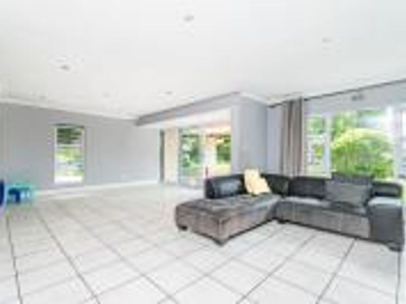 Spacious living area featuring neutral grey walls, large windows, and tiled flooring, with direct access to the outdoor patio area.