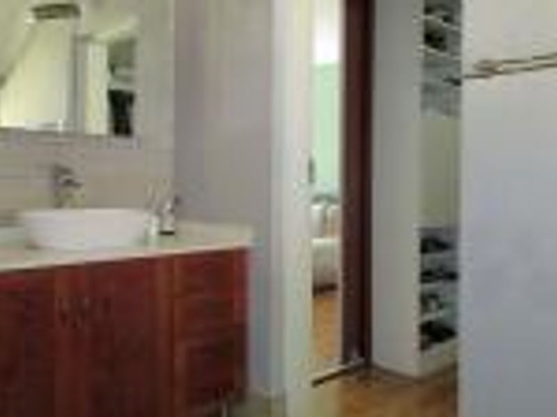 A bathroom featuring a wooden vanity with a vessel sink, wall mirror, and adjacent built-in shelving unit.