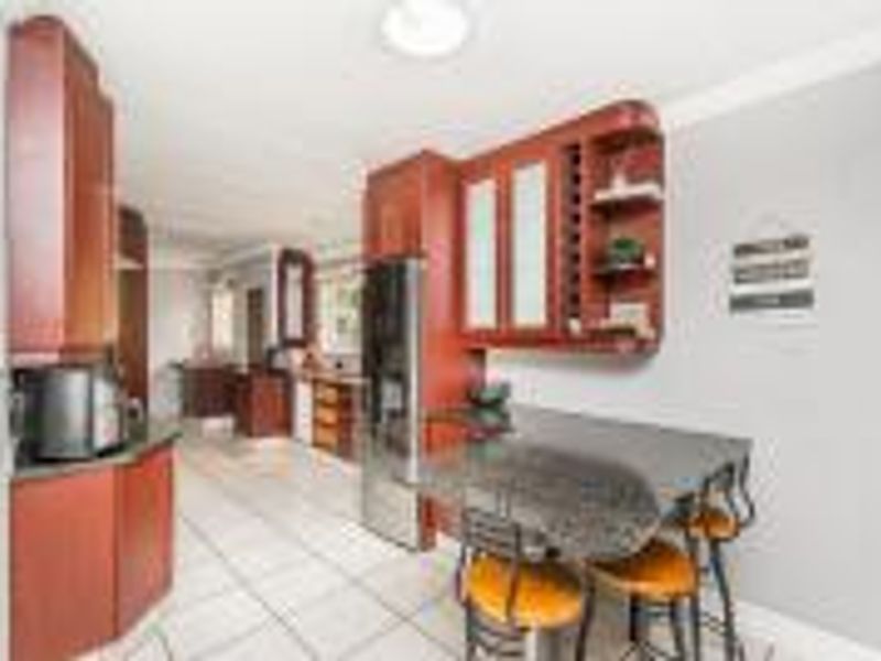 A functional kitchen featuring dark wood cabinetry, stone countertops, and tiled flooring, with an integrated breakfast bar area.