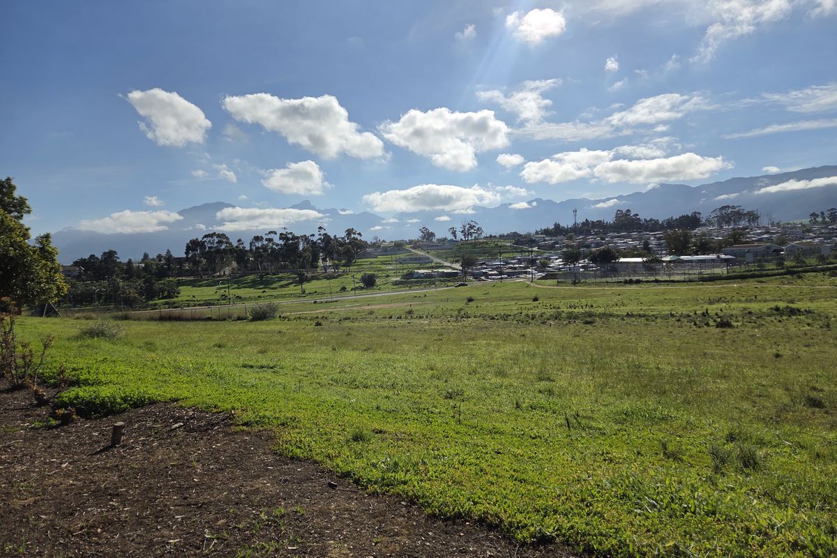 A scenic view of the surrounding landscape, featuring open green fields and distant mountain ranges under a clear blue sky.