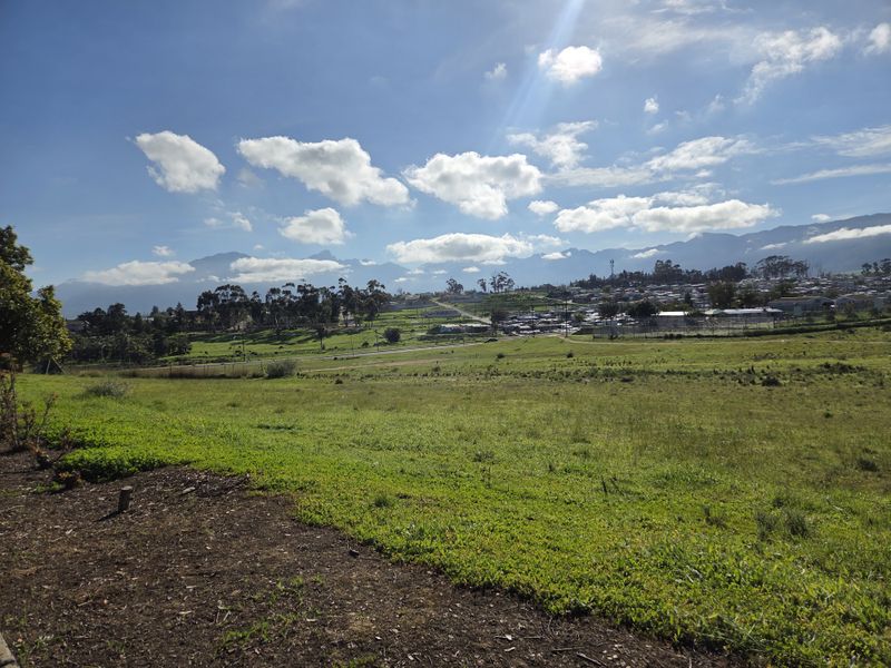 A scenic view of the surrounding landscape, featuring open green fields and distant mountain ranges under a clear blue sky.