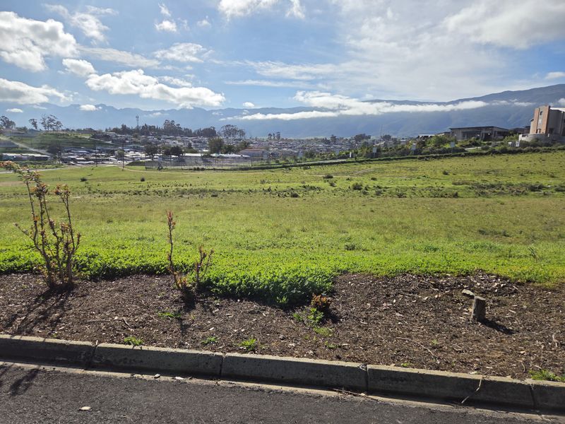 A view of a vacant residential plot with surrounding landscape and distant mountain scenery.