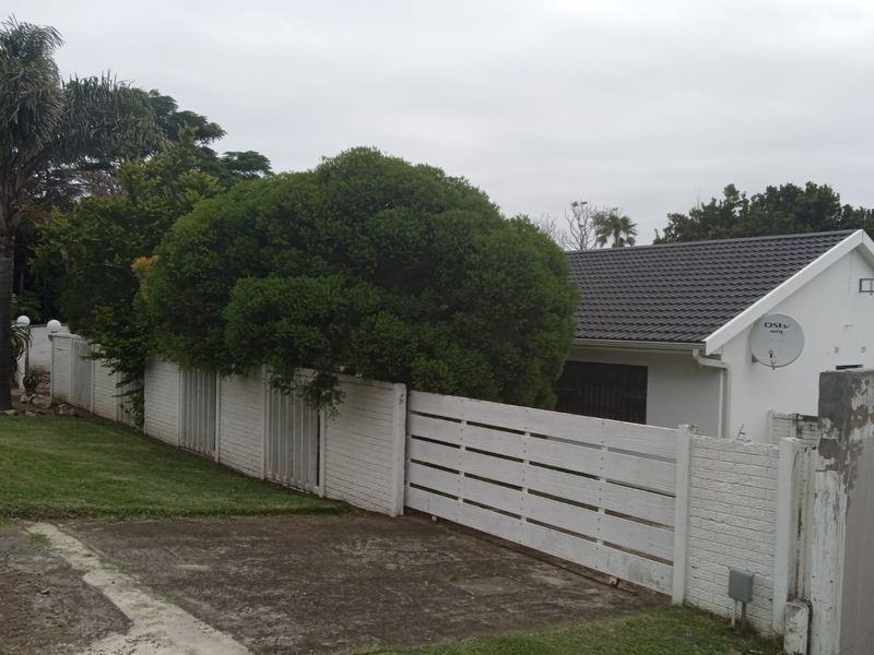 Front exterior view of the property featuring a tiled roof, white painted brick boundary wall, timber gate, and concrete driveway.