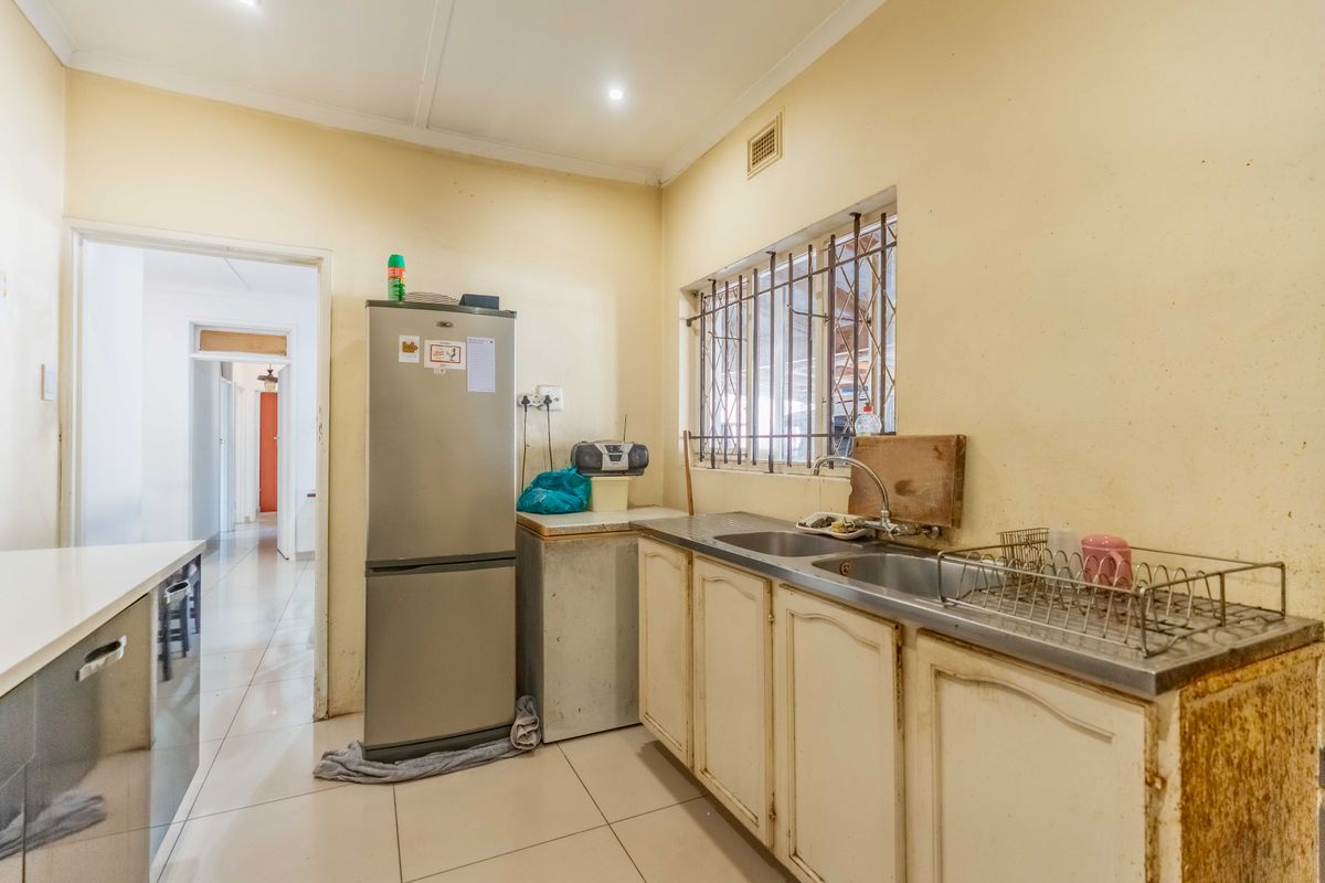 A functional kitchen featuring tiled flooring, a stainless steel double sink, and built-in cabinetry, offering potential for modernization and cosmetic updates.