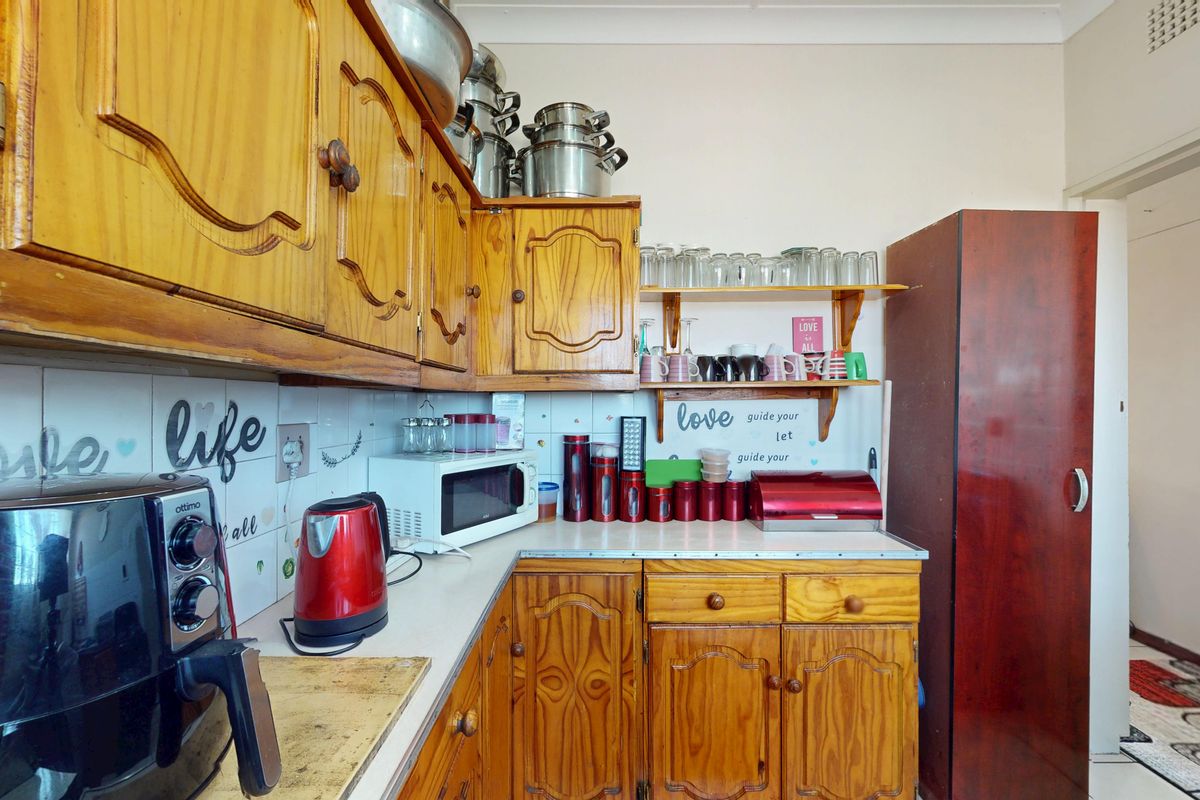 A functional kitchen featuring traditional wooden cabinetry, laminate countertops, and a tiled backsplash, offering a classic layout with ample storage space.