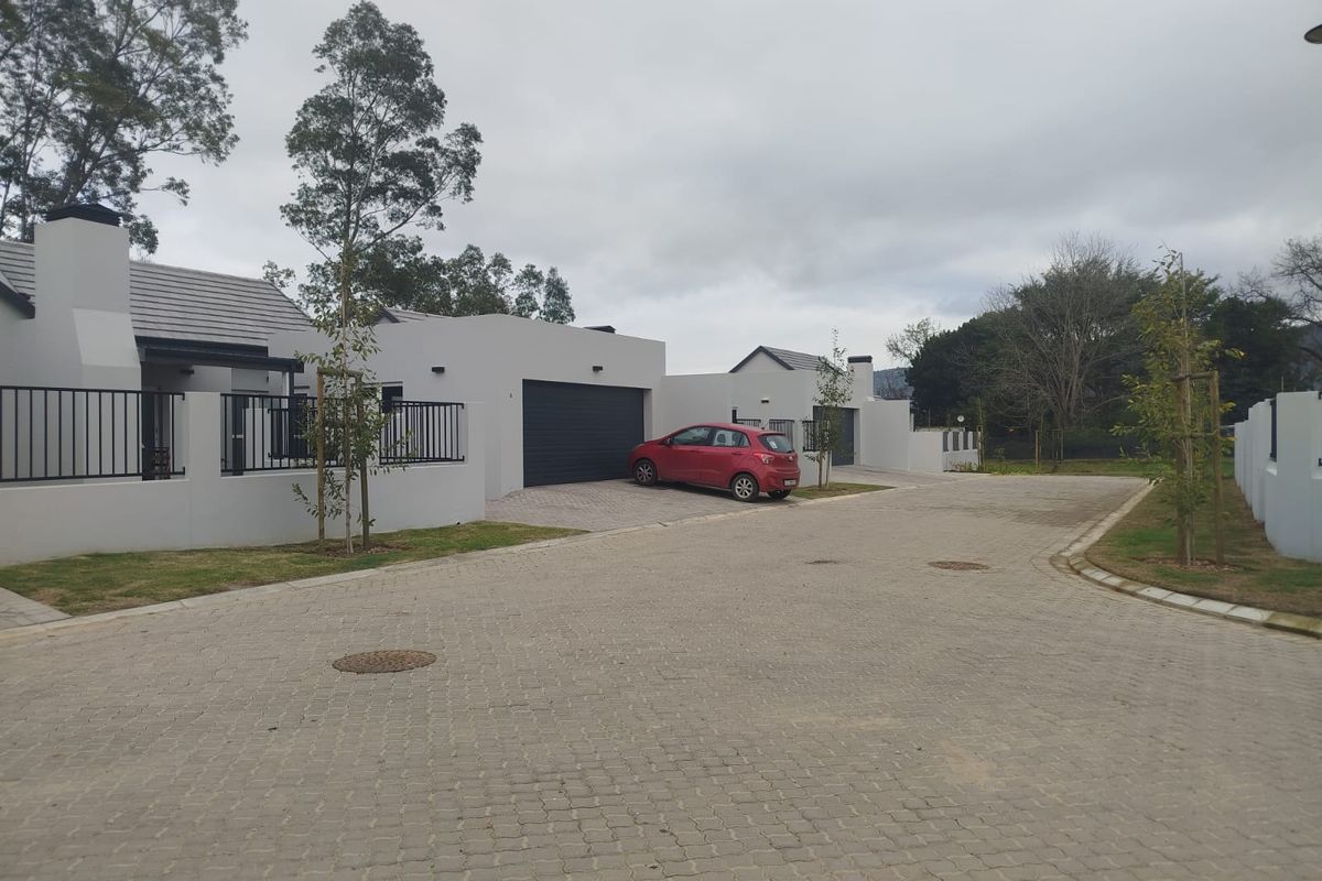 Front exterior view of a modern residential property featuring a paved driveway, garage, and clean architectural lines in a quiet estate setting.