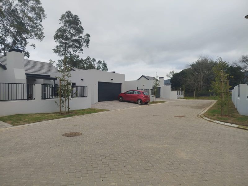 Front exterior view of a modern residential property featuring a paved driveway, garage, and clean architectural lines in a quiet estate setting.