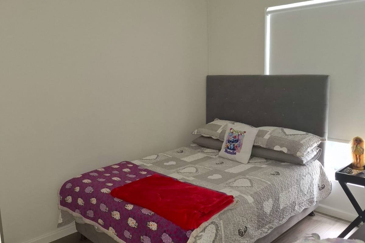 A clean and well-maintained bedroom featuring neutral wall finishes, modern laminate flooring, and a functional roller blind for privacy.