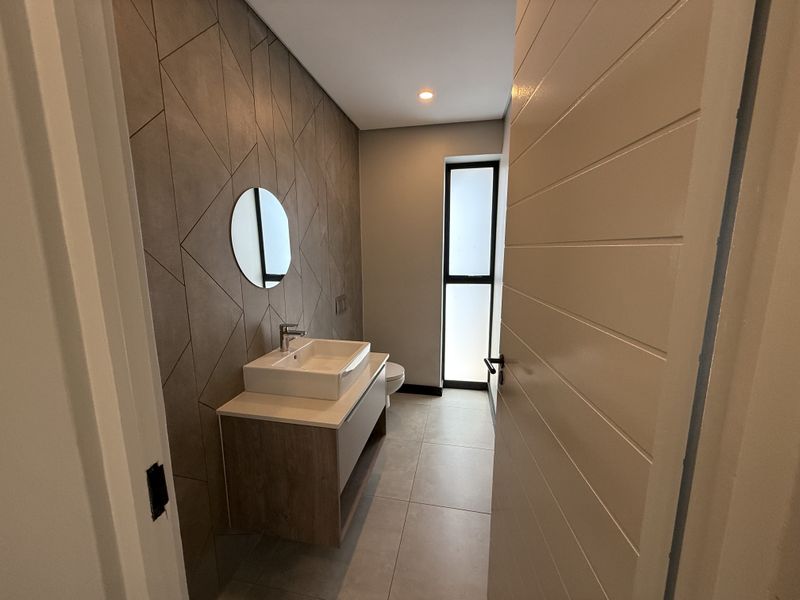 Modern bathroom featuring a floating vanity with a vessel sink, stylish geometric wall tiles, and a frosted glass window for natural light.