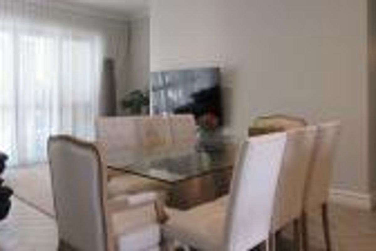 A bright living and dining area featuring tiled flooring and large sliding glass doors that provide access to the outdoor space.