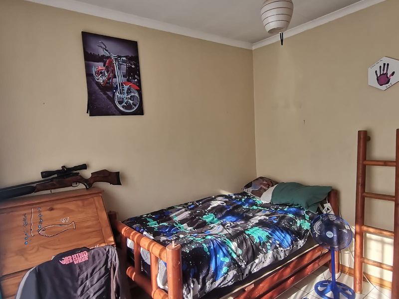 A bedroom featuring tiled flooring and a pendant light fixture, showing signs of wear on the walls and ceiling.