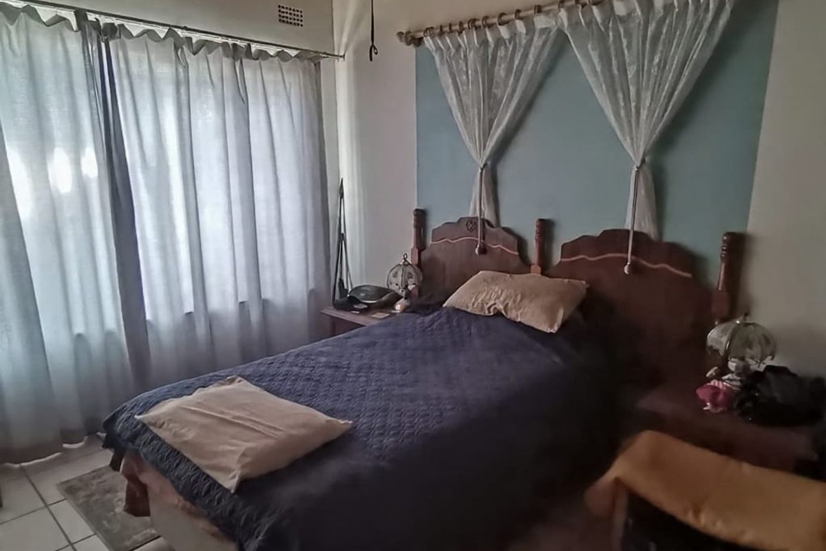A bedroom featuring a timber ceiling, tiled flooring, and a large window, offering a functional space with potential for cosmetic updates.